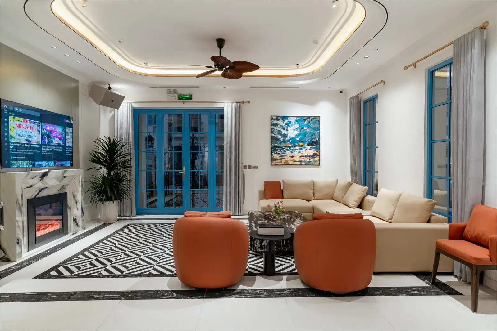 Phòng khách với cửa kính khung xanh, sofa và ghế bành màu cam