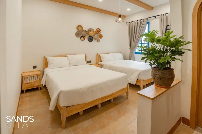 Phòng ngủ hai giường Sands Villa C6-16 với rèm xám và chậu cây xanh